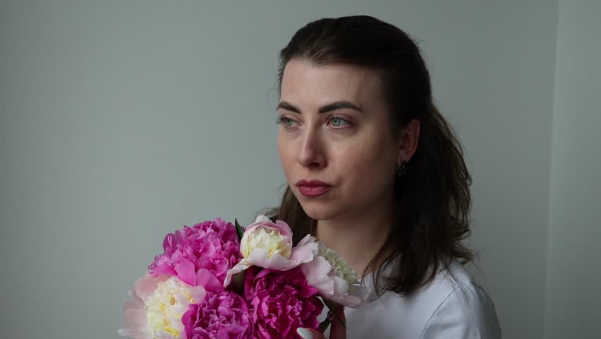 The girl sniffs a bouquet of peonies and looks into the distance. Bouquet of flowers
