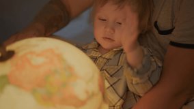 Boy Playing With Globe with father. Little kid Looking at lighting sphere, happy time with daddy. Exploring World, Learning. Child care, sweet time before going sleep. Concept of family and childhood. - Powered by Shutterstock - Get 15% off with code: PIKWIZARD15