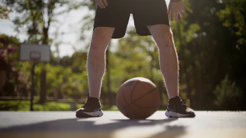Basketball guy taking rest outdoors portrait. Young man tossing ball from hand to hand at open air stadium closeup. Positive teen posing after cardio training. Satisfied sportsman active lifestyle