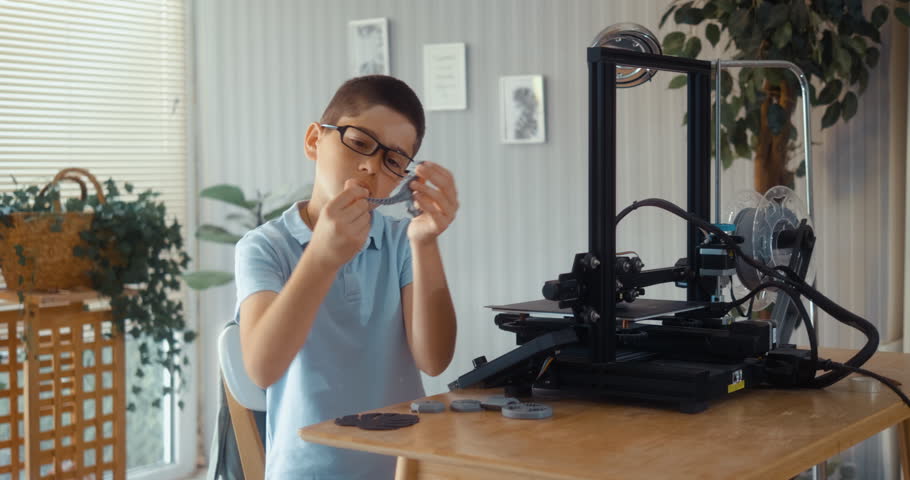 12-year-old boy models plastic toy dinosaurs using a 3D printer at home.