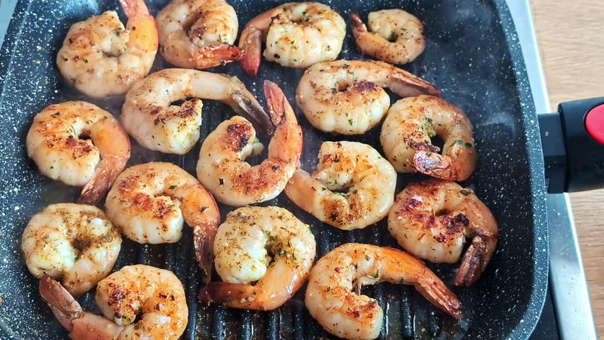 Juicy shrimps sizzle and brown in a hot pan during a cozy home cooking session.