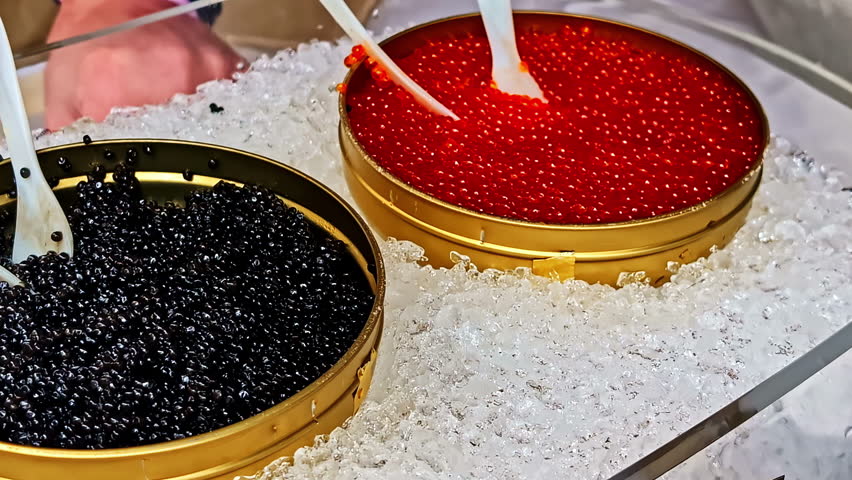 Display of red and black caviar in tins on crushed ice at seafood market