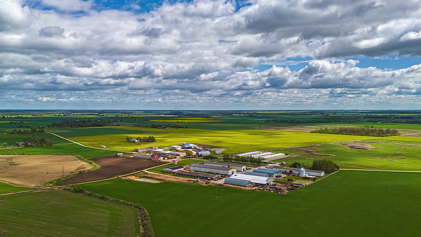 Large plantation and farmland landscape in Europe with crops growing in cultivated fields under a cloudscape aerial time apse