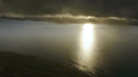 Drone captures sunbeam shining through storm clouds onto water, showcasing sun pillar or crepuscular rays lighting up a serene lake or sea landscape. - Powered by Shutterstock - Get 15% off with code: PIKWIZARD15