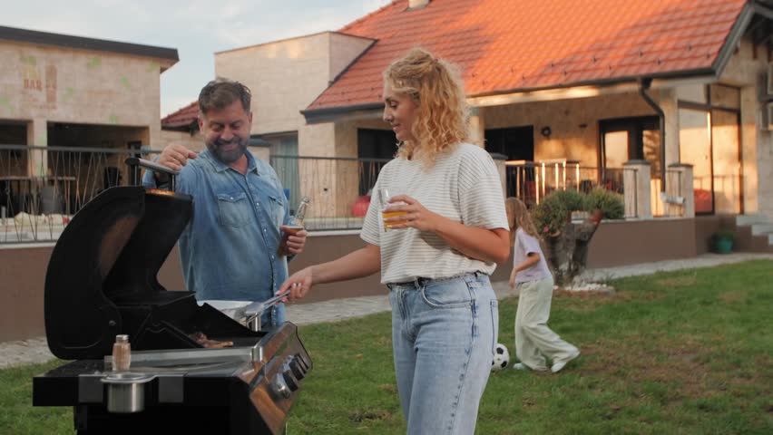 Family members enjoying summer barbecue, parents grilling while children play on lush backyard lawn, capturing genuine moments of togetherness and leisure