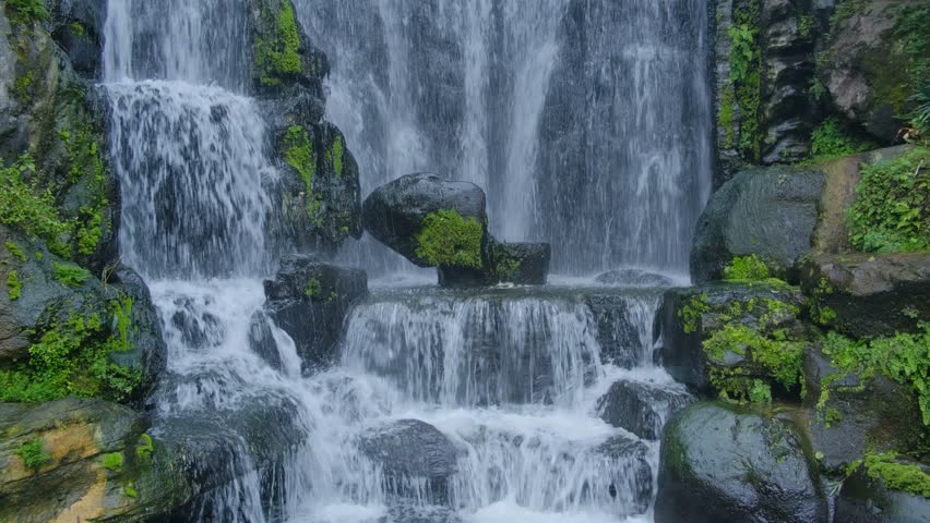 Waterfall over rocks and moss at temple in Taipei close up