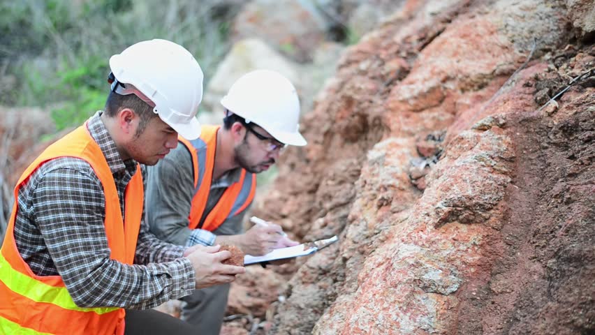 Expert geologists are working together to examine minerals in different layers of rock on a mountain to study the life and vegetation of the past.