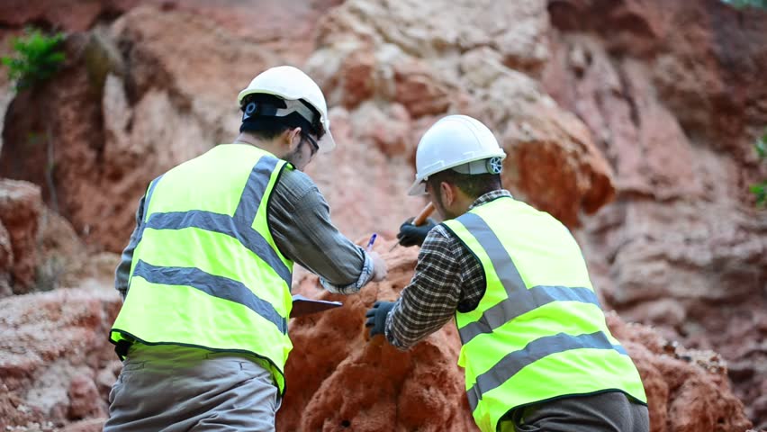 Expert geologists and explorers are working together to examine the rock layers in a mountain to determine the minerals in the rock layers.