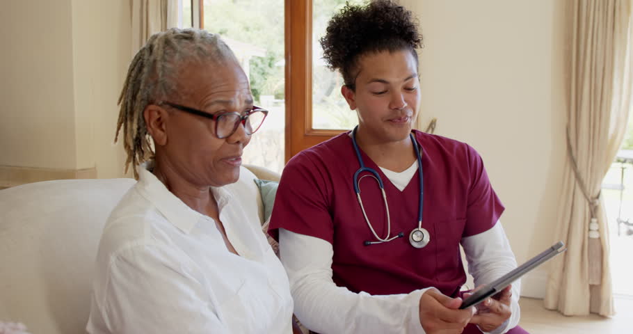 Healthcare professional in scrubs discussing care plan with senior woman at home. caregiver, assistance, support, senior care, consultation, home visit