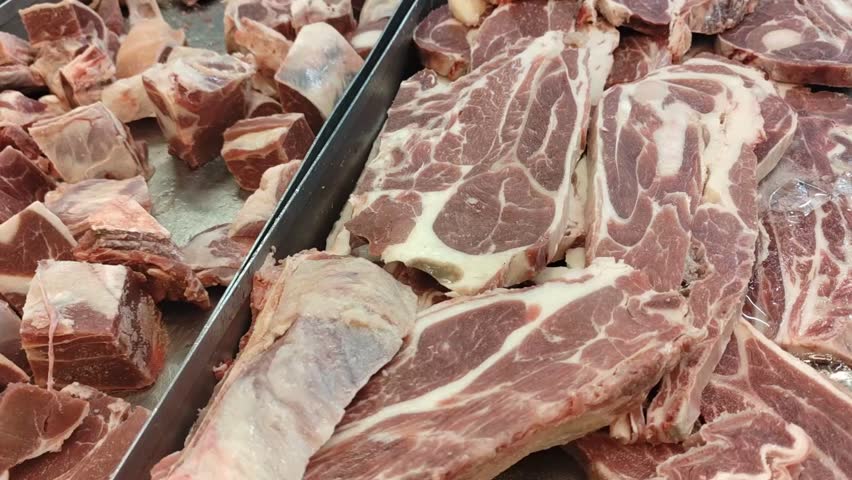 Slices of frozen beef neatly arranged on a tray in a supermarket. Ready for purchase, the meat is displayed under bright lighting, emphasizing its freshness and quality.