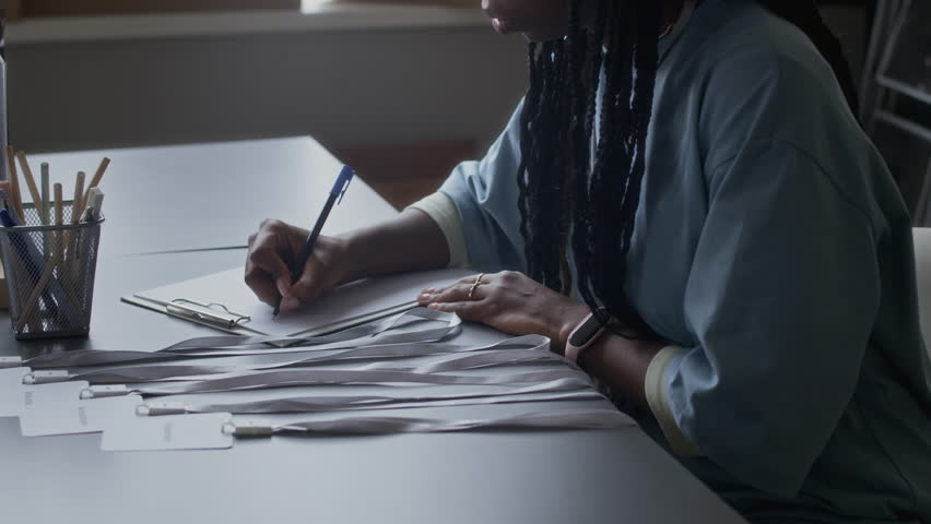 Cropped shot of young black woman registering new volunteer and giving badge and uniform at donation center