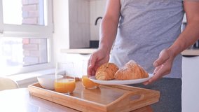A man serves breakfast with croissants and orange juice for two on a tray in the kitchen. Breakfast in bed - Powered by Shutterstock - Get 15% off with code: PIKWIZARD15
