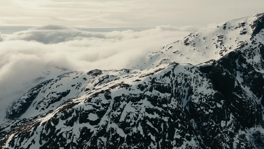 Clouds Moving On The Mountain Rock Covered With Snow In Lofoten, Norway. Aerial Drone Shot