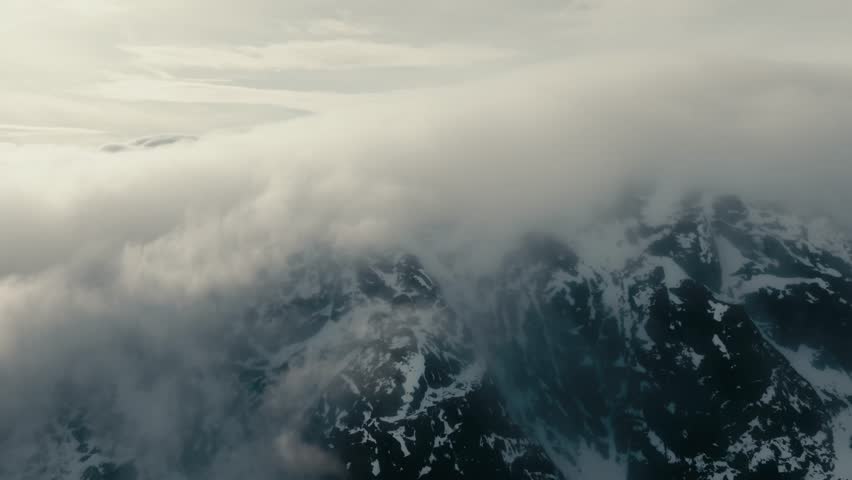 Clouds Over The Peak Of Snowy Mountains In Lofoten Islands, Nordland, Norway. - aerial shot