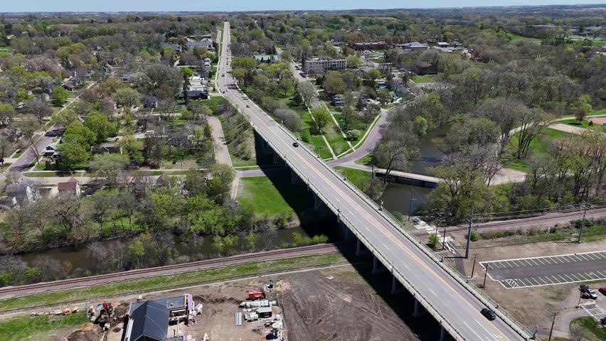 Drone slowly panning around bridge with cars driving on it. Viaduct bridge over Straight River in Faribault, Minnesota. Division Street to Highway 60