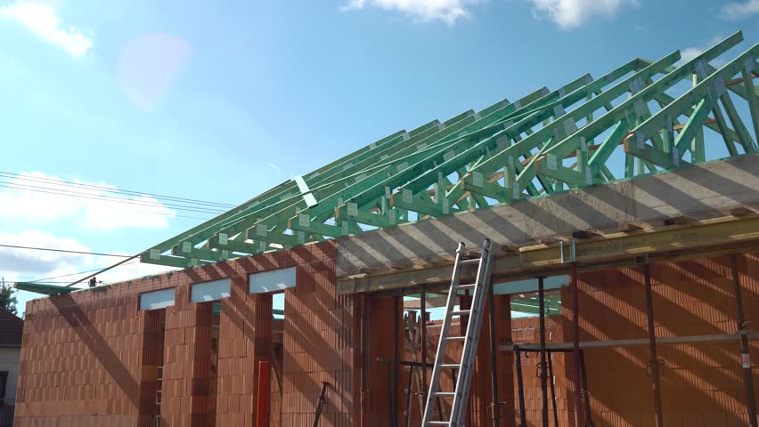Exterior of unfinished brick house with green timber trusses being installed