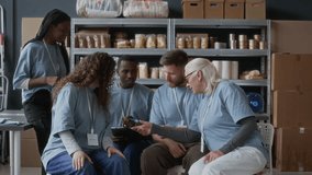 Medium long portrait of diverse team of volunteers in blue T-shirts looking at camera at food storage - Powered by Shutterstock - Get 15% off with code: PIKWIZARD15