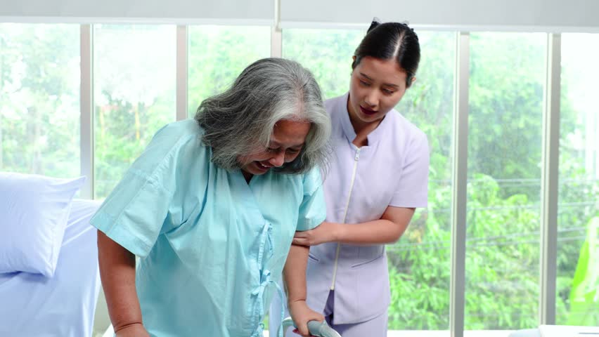 Attractive young asian woman or nurse take care senior old woman on cane or walker feeling helpful and empathy at nursing home or room hospital . Hip, knee and leg problem in older people.