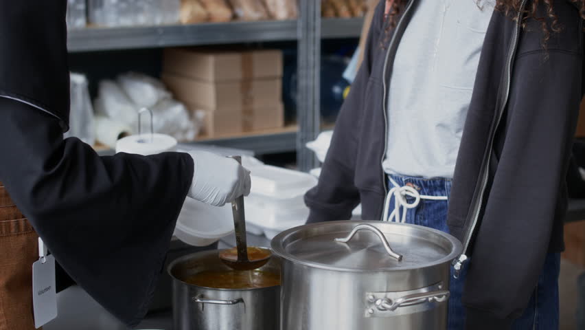 Cropped shot of African American nun sharing soup with young female refugee while working at aid center