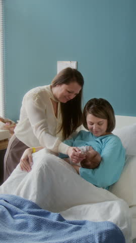 Mature Caucasian woman visiting her daughter and newborn granddaughter in maternity hospital, copy space