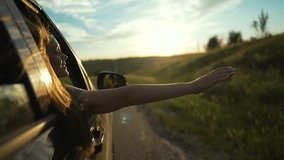 woman enjoys summer drive. Hand stretches out car window feeling warm breeze sunlight. Hair flows wind during golden hour. Carefree summer road trip embracing nature and freedom. Woman car hand summer - Powered by Shutterstock - Get 15% off with code: PIKWIZARD15