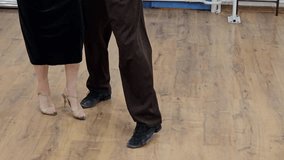 A man and woman are dancing tango on a wooden floor. The man is wearing black pants and the woman is wearing a black dress - Powered by Shutterstock - Get 15% off with code: PIKWIZARD15