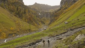 Hiking couple in breathtaking natural landscape with distant waterfall on cloudy day - Powered by Shutterstock - Get 15% off with code: PIKWIZARD15