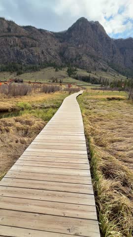 Wooden trail over marshy terrain near Blue Geyser Lake Aktash Altai Russia. Nature path guiding visitors to volcanic lake. High quality 4k footage