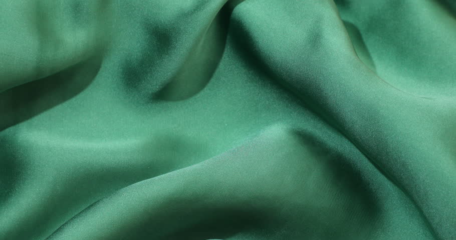 A closeup slow motion of green fabric background with soft texture and gentle folds - suitable for commercial textile industry advertisements