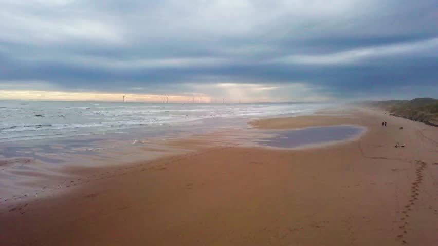 Serene beach view in Scotland, gentle waves washing up on golden sand