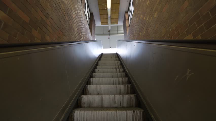 An escalator ride up toward a bright exit