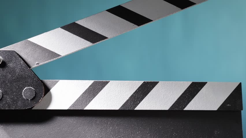 Cinematic production moment, clapperboard snapping shut, creating a dust effect in the studio