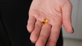 Hand holding two softgel capsules with vitamins or supplements. Close-up health concept on dark background. - Powered by Shutterstock - Get 15% off with code: PIKWIZARD15