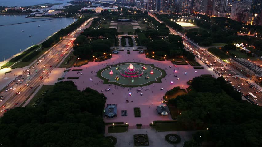 A rotating drone timelapse of Chicago’s Buckingham Fountain glowing with colorful lights as the surrounding city comes alive after sunset.