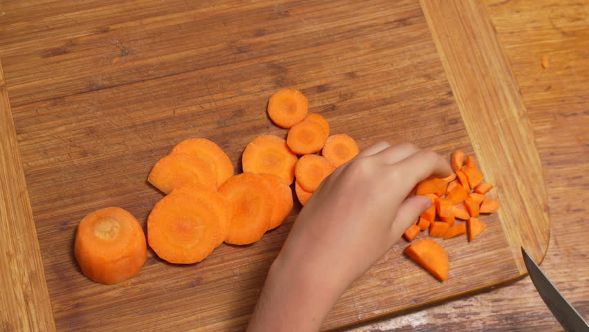 Carrots Chopping Board Kitchen: Child prepares sliced and diced carrots on wooden board for cooking.