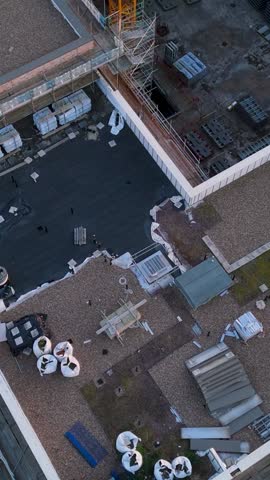 Portrait top-down drone shot of yellow crane over derelict urban construction site