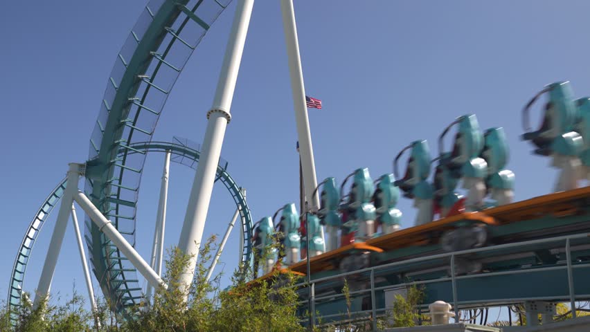 Enjoy breathtaking views from the coaster's height while feeling the rush of adrenaline as it twists and turns through the air at amusement park on a sunny day.