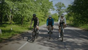 Positive cyclists group with helmets and goggles rides bicycles along country road. Young sportsmen enjoy active hobby in green park on summer day - Powered by Shutterstock - Get 15% off with code: PIKWIZARD15