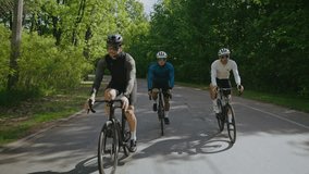 Cyclists in hard hats and goggles ride fast bikes along country road. Men athletes on race bicycles speed across green summer park. Active lifestyle - Powered by Shutterstock - Get 15% off with code: PIKWIZARD15