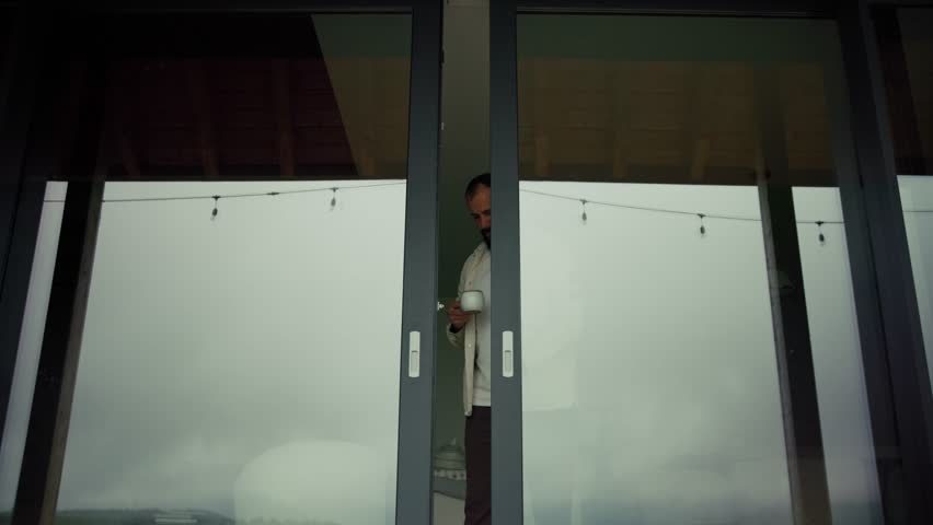 Homeowner drinks coffee on the porch of his modern, minimalist home