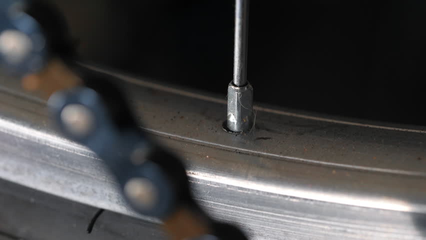Detailed view of bike wheel spoke and rim interface.
Video footage of a close-up view of a bicycle spoke nipple where it meets the metal rim.