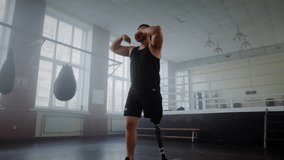 Young sportsman with prosthetic leg warms up arms before boxing training in gym. Man with disability shows determination motivation and inclusivity in sports - Powered by Shutterstock - Get 15% off with code: PIKWIZARD15