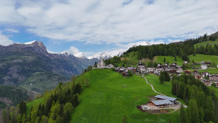 Aerial view of Selva di Cadore village surrounded by green hills and the dramatic Dolomite mountains