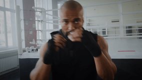 Powerful black boxer throws punches during intense training session in gym POV. African American man shows strength and dedication preparing for fight by ring - Powered by Shutterstock - Get 15% off with code: PIKWIZARD15