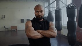Muscular African American boxer with serious expression crosses arms in gym. Baldhead black bodybuilder sportsman with beard ready for sparring in fighting club - Powered by Shutterstock - Get 15% off with code: PIKWIZARD15