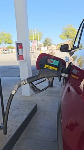 Laveen, AZ. USA - April 9, 2025: Vertical Footage of parked vehicle with Gas Hose in tank at Shell Gas Station. 