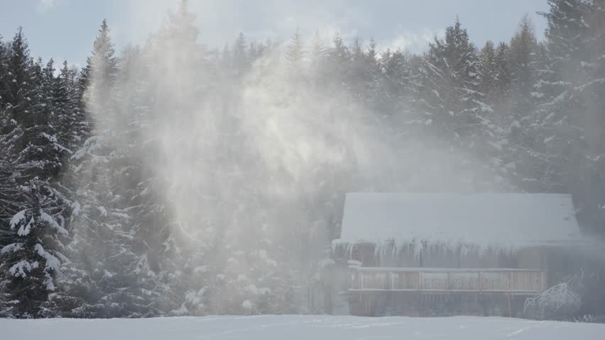A rustic wooden cabin features heavy icicles and frosted wood beneath its snowy roofline as snow whirls around. Rapallax video.