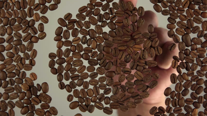 Whole grains are roasted coffee. Man's finger paints the symbol of coffee