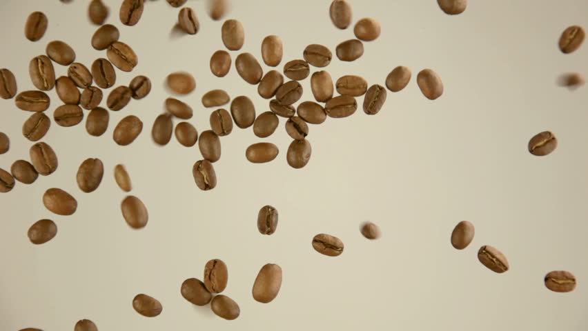 Beige background. Roasted coffee beans fall from above
