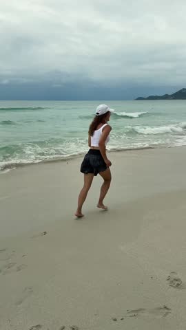 A Girl Joyfully Running on the Beach Beneath Cloudy Skies in a Scenic Environment